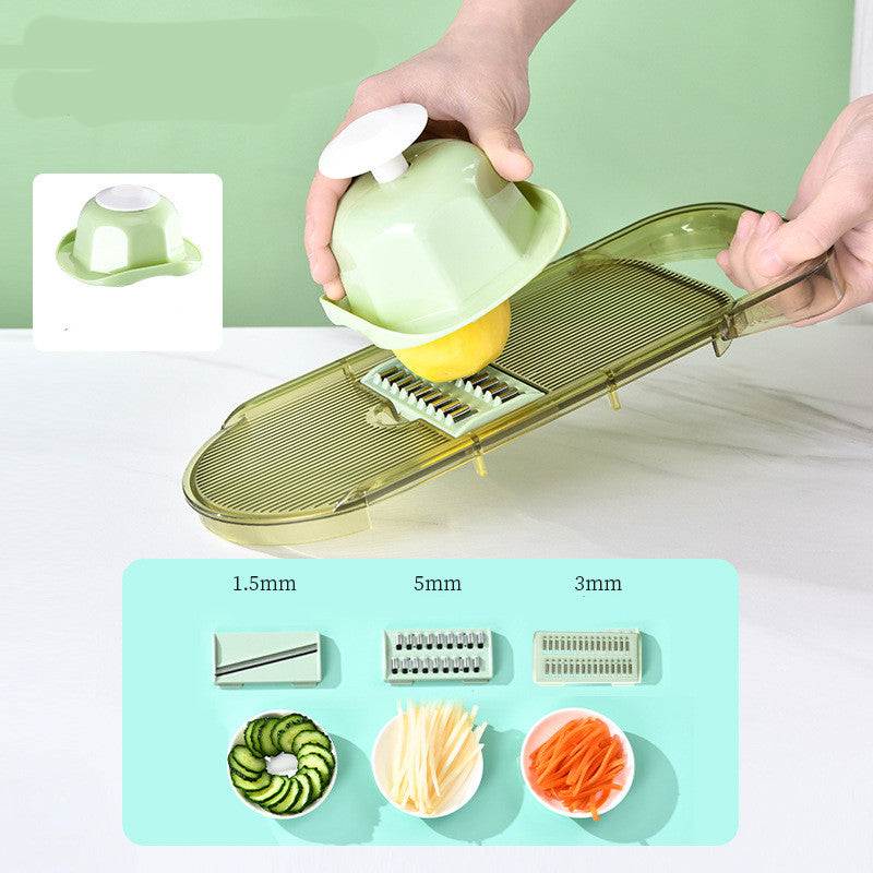 All-in-One Mandoline Slicer with transparent yellow plastic frame and multiple stainless steel blades slicing a yellow vegetable using a green hand protector