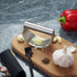 Best garlic crusher stainless steel rocker with finely minced garlic on wooden board near garlic cloves and red pepper
