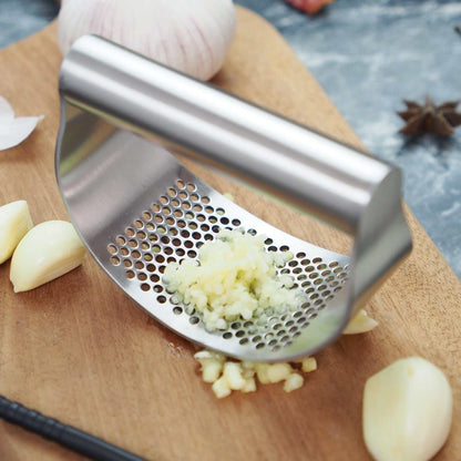 Best garlic crusher stainless steel rocker with ergonomic handle and finely minced garlic on a wooden board
