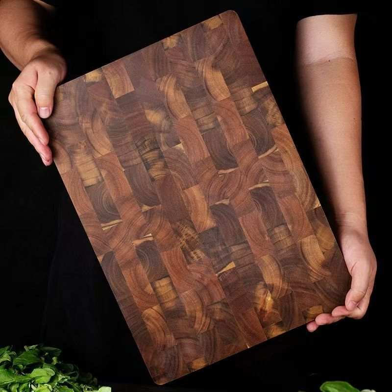 cutting wood board made from solid dark acacia mangium wood with a woven checkerboard pattern held by a person